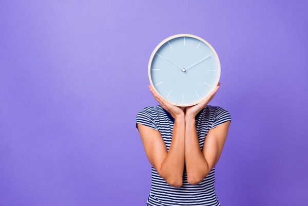 a woman holding a clock on her face