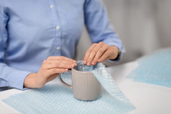 a person wrapping a mug with bubble wrap