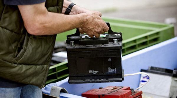 a mechanic placing an old car battery inside a box
