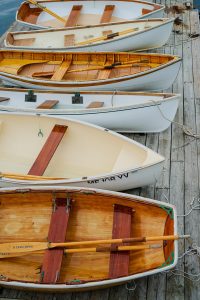 6 small wooden boats lined up on a deck. 