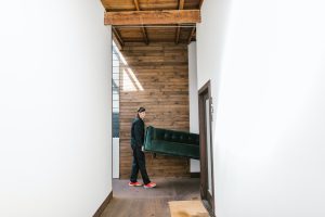 guy moving a green couch with wooden floors