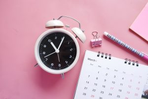 Pink background with a clock and calendar