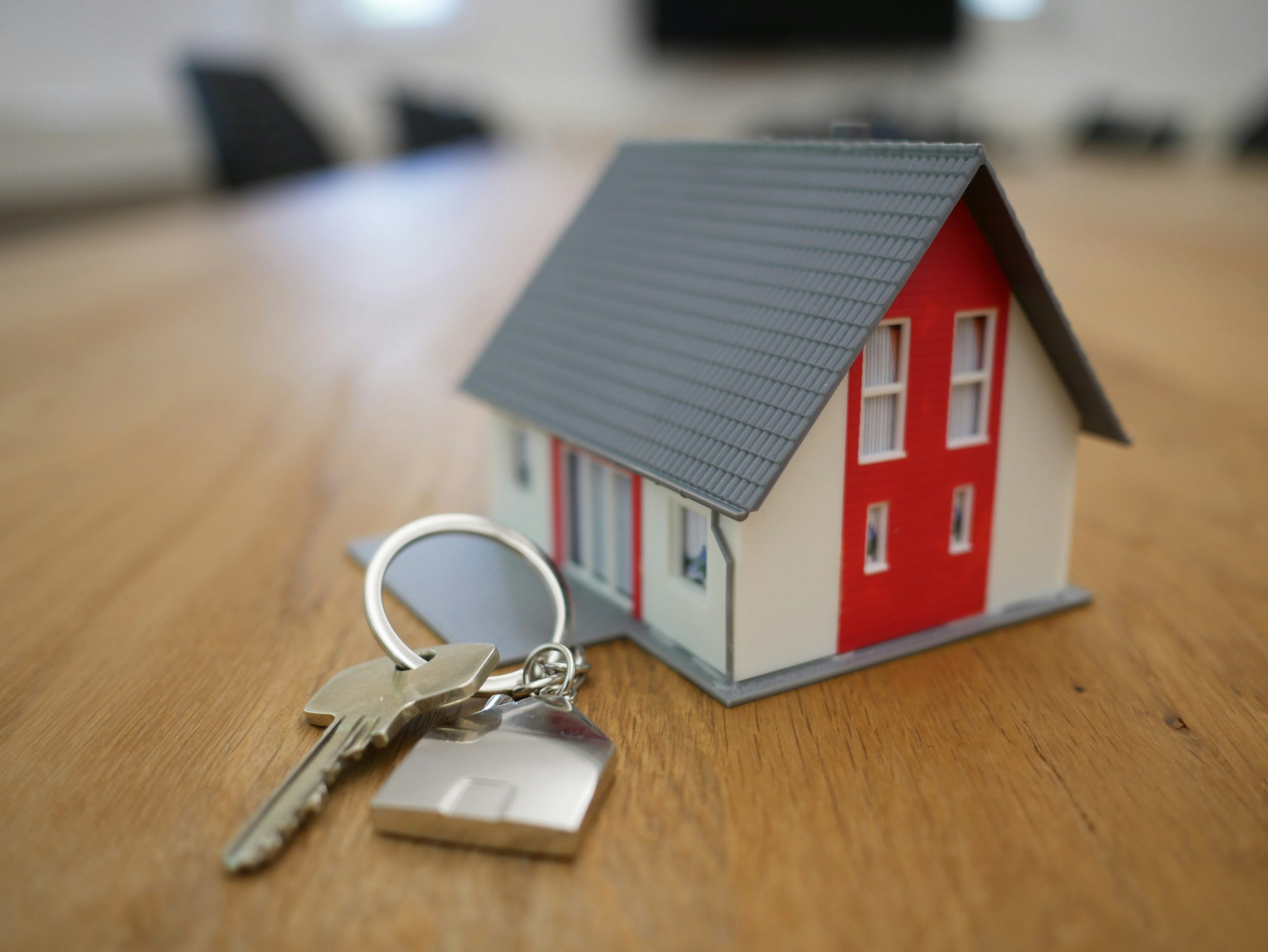 white and red wooden miniature house next to keychain to show purchase of new house/life transition
